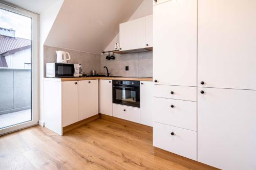 a kitchen with white cabinets and a large window at Katowicka Premium Apartment in Kraków