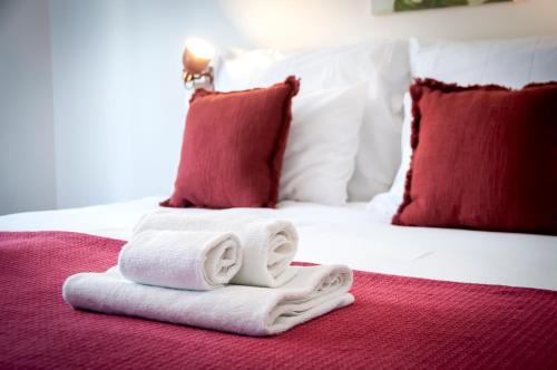 a pile of towels on a bed with red pillows at bed&breakfast Bohemian in Rovinj