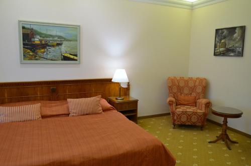 a hotel room with a bed and a chair at Bristol Kralovska Vila in Karlovy Vary