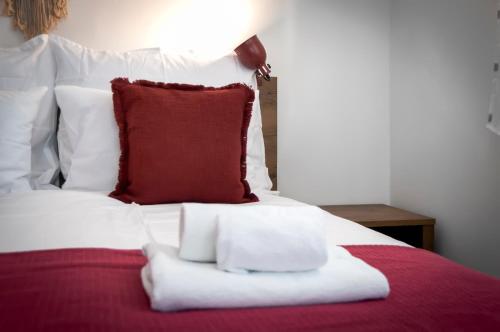 a bed with a red pillow and towels on it at bed&breakfast Bohemian in Rovinj