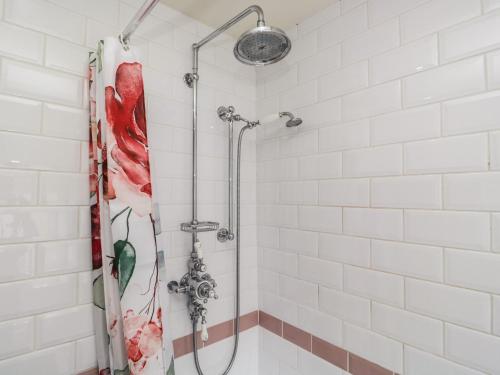 a shower in a white tiled bathroom at 14 Low Row in Holker