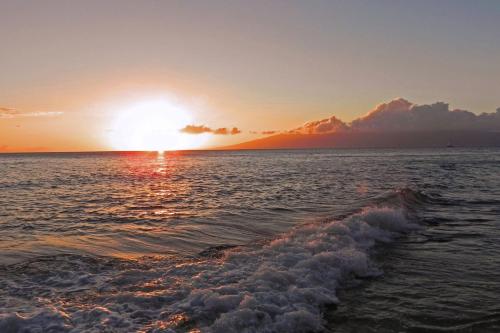a sunset over the ocean with a wave at Mahana at Kaanapali in Kaanapali