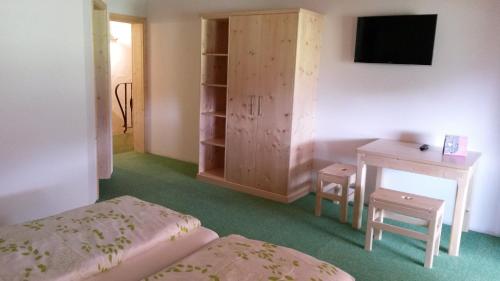 a room with two beds and a desk and a television at Pension Biobauernhof Hinteraltensberg in Auffach