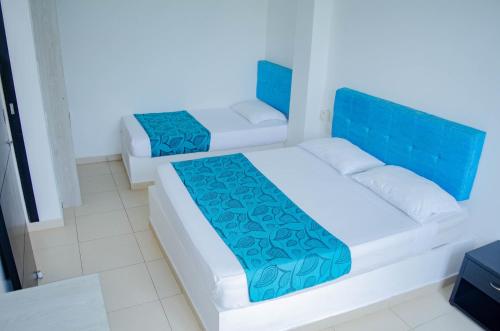 two beds in a room with blue and white at Apartahotel y Hotel Sofichic Boutique in Barranquilla