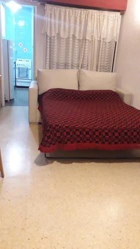 ein Schlafzimmer mit einem Bett mit einer roten Bettdecke und einem Fenster in der Unterkunft Departamento monoambiente in Mar del Plata