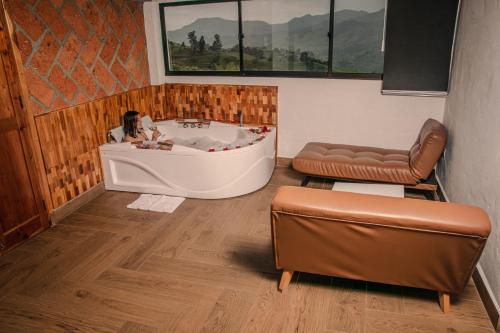 a woman sitting in a bath tub in a room at Hotel Santa Laura in Jericó