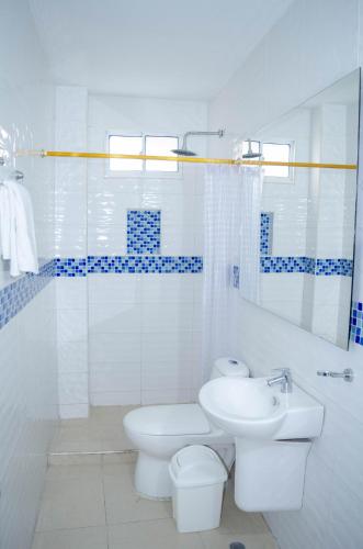 a white bathroom with a toilet and a sink at Apartahotel y Hotel Sofichic Boutique in Barranquilla