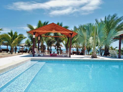 a swimming pool with a gazebo and palm trees at Punta del Norte Bungalows in Canoas de Punta Sal