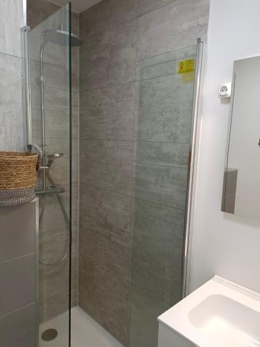 une douche avec une porte vitrée à côté d'un lavabo dans l'établissement SPARKLE-STUDIO PROCHE PLAGE PLEIN CENTRE PARKING WIFI TERRASSE - La Grande Motte, à La Grande Motte