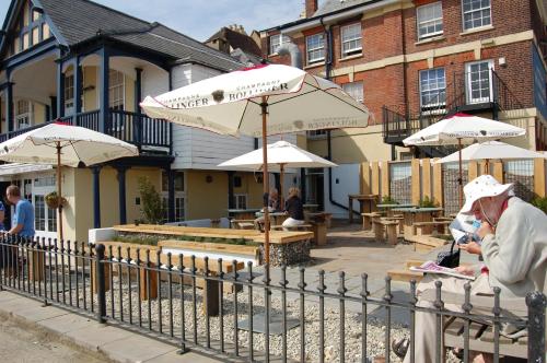 a woman standing next to a fence with umbrellas at Royal Hotel in Deal