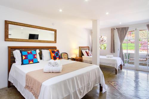 a bedroom with two beds and a mirror at Boutique Hotel Carpe Diem in Paraty