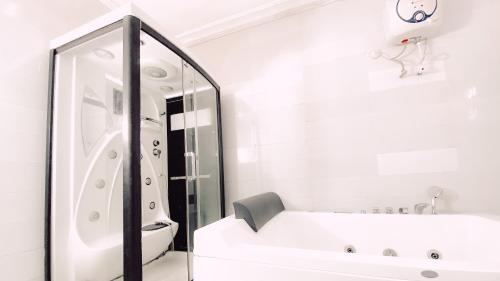 a white bathroom with a tub and a mirror at Royal Court Lounge & Boutique Hotel in Port Harcourt