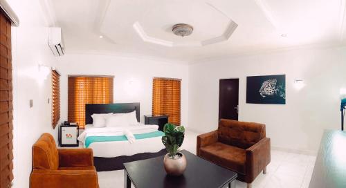 1 dormitorio con 1 cama, mesa y sillas en Royal Court Lounge & Boutique Hotel, en Port Harcourt