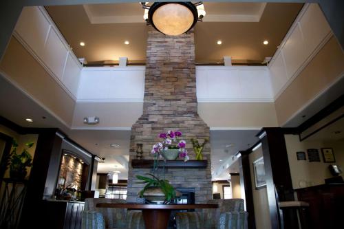 a brick fireplace in a lobby with a table and flowers at Sonesta ES Suites San Francisco Airport San Bruno in San Bruno