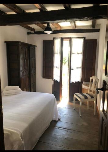 a bedroom with a bed and a chair and windows at La Saleta in Bejes