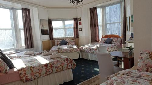 a room with four beds and a table and windows at Mellory hotel in Blackpool