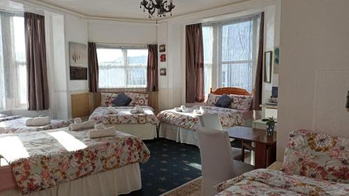 a hotel room with three beds and a table and chairs at Mellory hotel in Blackpool