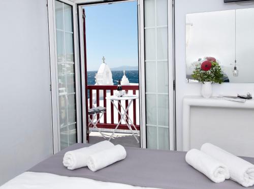 - une chambre avec 2 serviettes sur un lit et un balcon dans l'établissement Myconian Little Venice Elite Suites with Sea View, à Mykonos