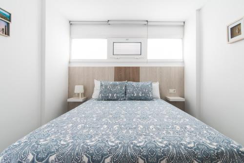 um quarto com uma cama com um edredão azul e branco em Home2Book Sunny Beach Maspalomas Playa del Inglés em Playa del Inglés