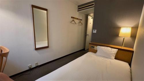 Habitación pequeña con 2 camas y espejo. en Ueno Terminal Hotel, en Tokio
