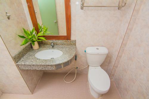 a bathroom with a toilet and a sink with a mirror at Sutus Court 4 in Pattaya