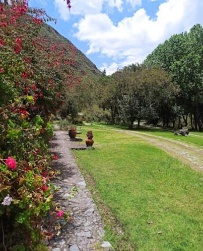 a path in a field with flowers and trees at Inti Punku Valle Sagrado Hotel in Urubamba