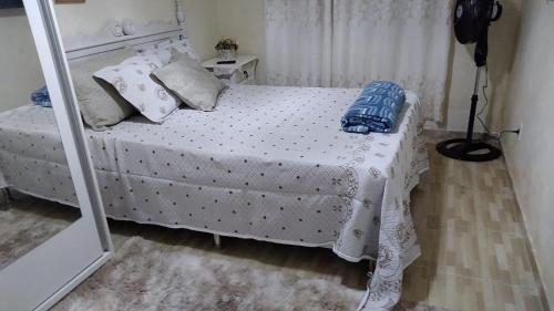 a bedroom with a bed with a white bedspread and a mirror at Casa tipo sobrado. in Arraial do Cabo