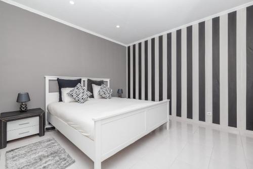 sypialnia z białym łóżkiem i ścianą w paski w obiekcie HOUSE-4YOU Apartamento Moderno w Lagosie