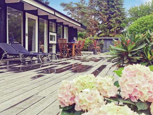 a deck with chairs and flowers in front of a house at 5 person holiday home in Hornb k in Hornbæk