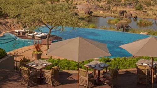 
a patio area with tables, chairs and umbrellas at Four Seasons Safari Lodge Serengeti in Banagi
