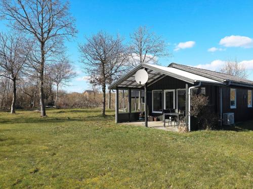 a small black house in a field with trees at 2 person holiday home in Thyholm-By Traum in Thyholm