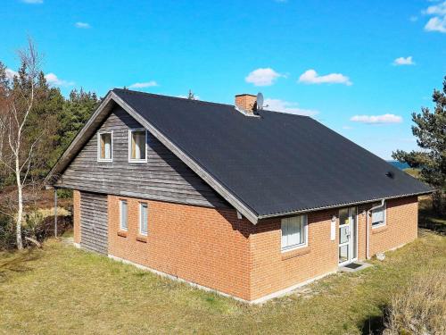 a red brick house with a black roof at 8 person holiday home in Thyholm in Thyholm