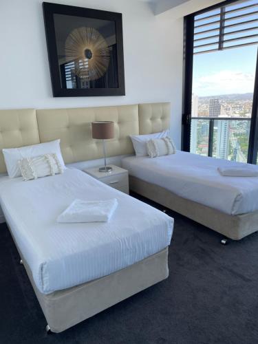 黄金海岸4 Bedroom Huge Sub Penthouse Oracle Level 31 Magnif VIEWS 260m2 Family Skyhome Sleeps 8 Adults and 2 Children, Sofa Bed Portacot, High Chair Central to Everything Resort Skyhome 5 STAR Luxury的带窗户的酒店房间里有两张床
