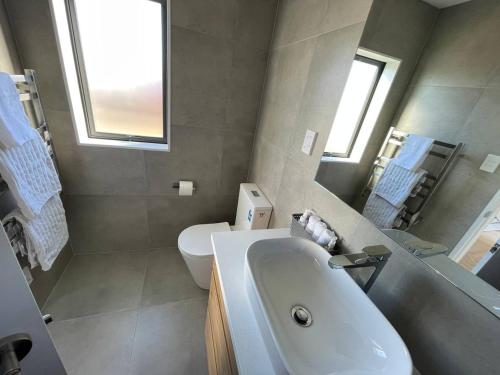 a bathroom with a white sink and a toilet at 4 bedroom home fully furnished in Papakura, Auckland in Auckland