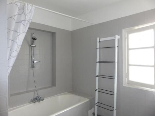 La salle de bains blanche est pourvue d'une baignoire et d'une fenêtre. dans l'établissement holiday home, Perros-Guirec, à Perros-Guirec
