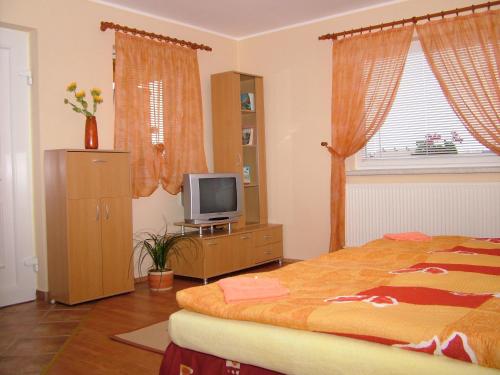 Dormitorio con cama y tocador con TV en Horváthapartman, en Bük
