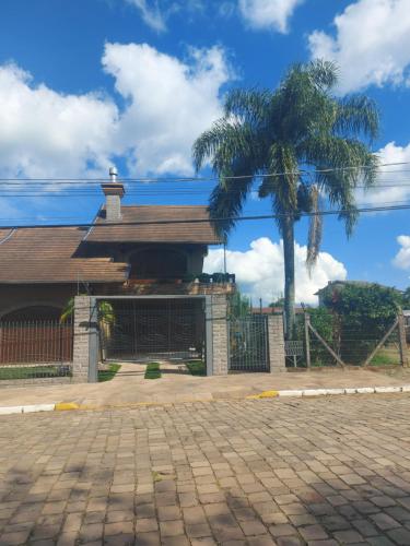 a building with a gate and a palm tree at Casa de Pedra-Vale dos Vinhedos -RS in Monte Belo