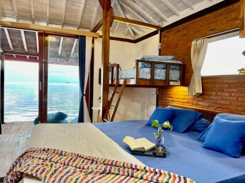 a bedroom with a bed with a view of the ocean at Omah Alchy Cottages in Karimunjawa