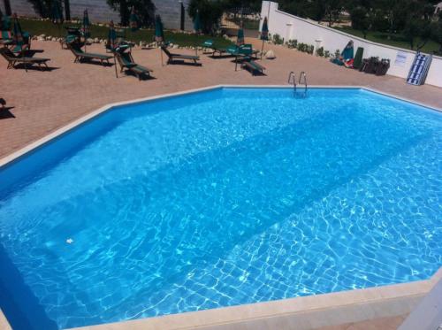 a large blue swimming pool with chairs and tables at B&B Terra Serena in Santa Cesarea Terme