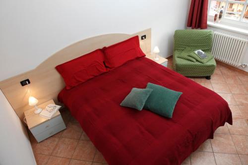 a bedroom with a red bed and a green chair at Residenza Andreotti in Ossana