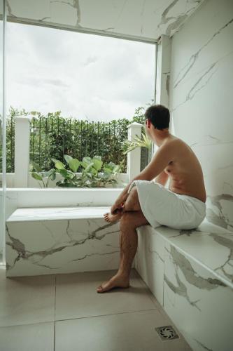 a man sitting on a window sill in a bathroom at Hotel Boutique El Triángulo in Armenia