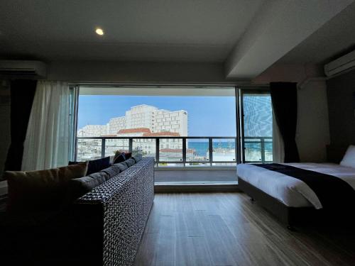 a bedroom with a bed and a couch and a large window at Coral Palace Onna by Sunset Avenue in Onna