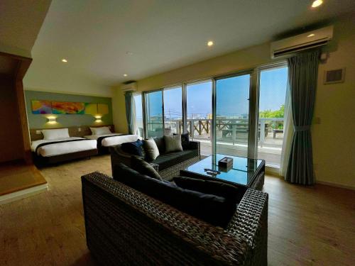 a living room with a couch and a room with a bed at Coral Palace Onna by Sunset Avenue in Onna