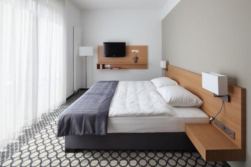 a bedroom with a large bed and a tv on the wall at Hotel Otterbach in Bietigheim-Bissingen
