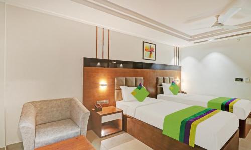 a hotel room with a bed and a chair at Treebo Emora Grand in Yelahanka