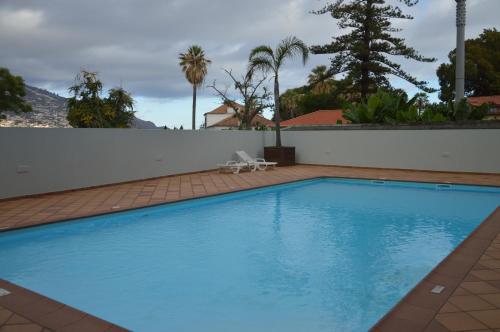 a large blue swimming pool next to a white wall at Villa Jasmineiro in Funchal