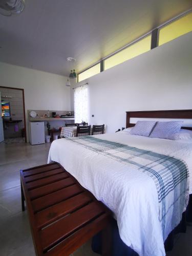 a bedroom with a large bed with a bench next to it at Agutipaca Bungalows in Bagaces