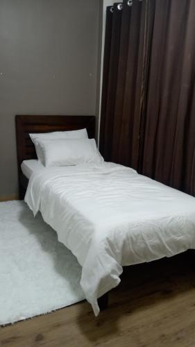 a bed with white sheets and a wooden headboard at A2J Luxury BGC 2BR Loft Near Malls, Burgos Circle in Manila