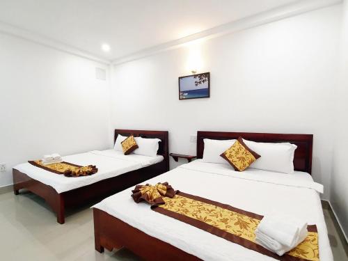 two beds in a room with white walls at Khách sạn Thái Bình in Con Dao