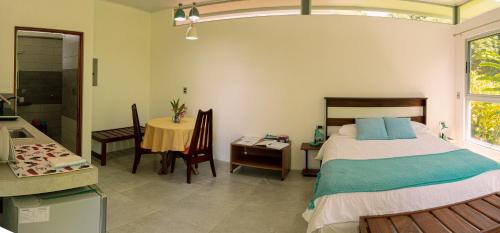a bedroom with a bed and a table and a bathroom at Agutipaca Bungalows in Bagaces